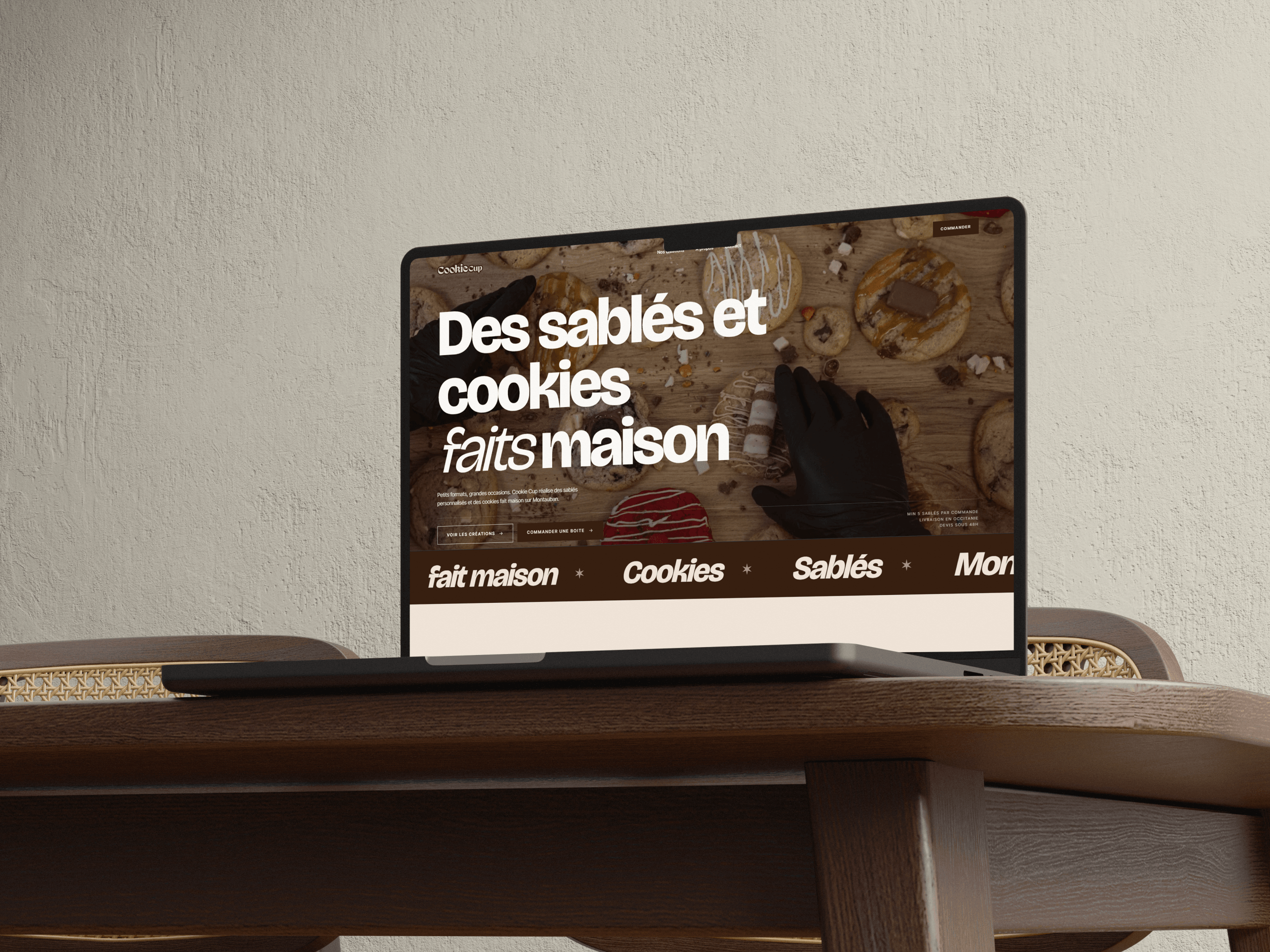 Page d'accueil du site Cookie Cup sur un portable : l'accroche « Des sablés et cookies faits maison » sur une photo de plan de travail.