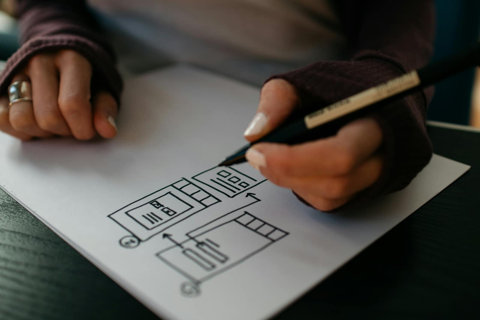 Main qui dessine au crayon la structure d’une page, blocs et colonnes